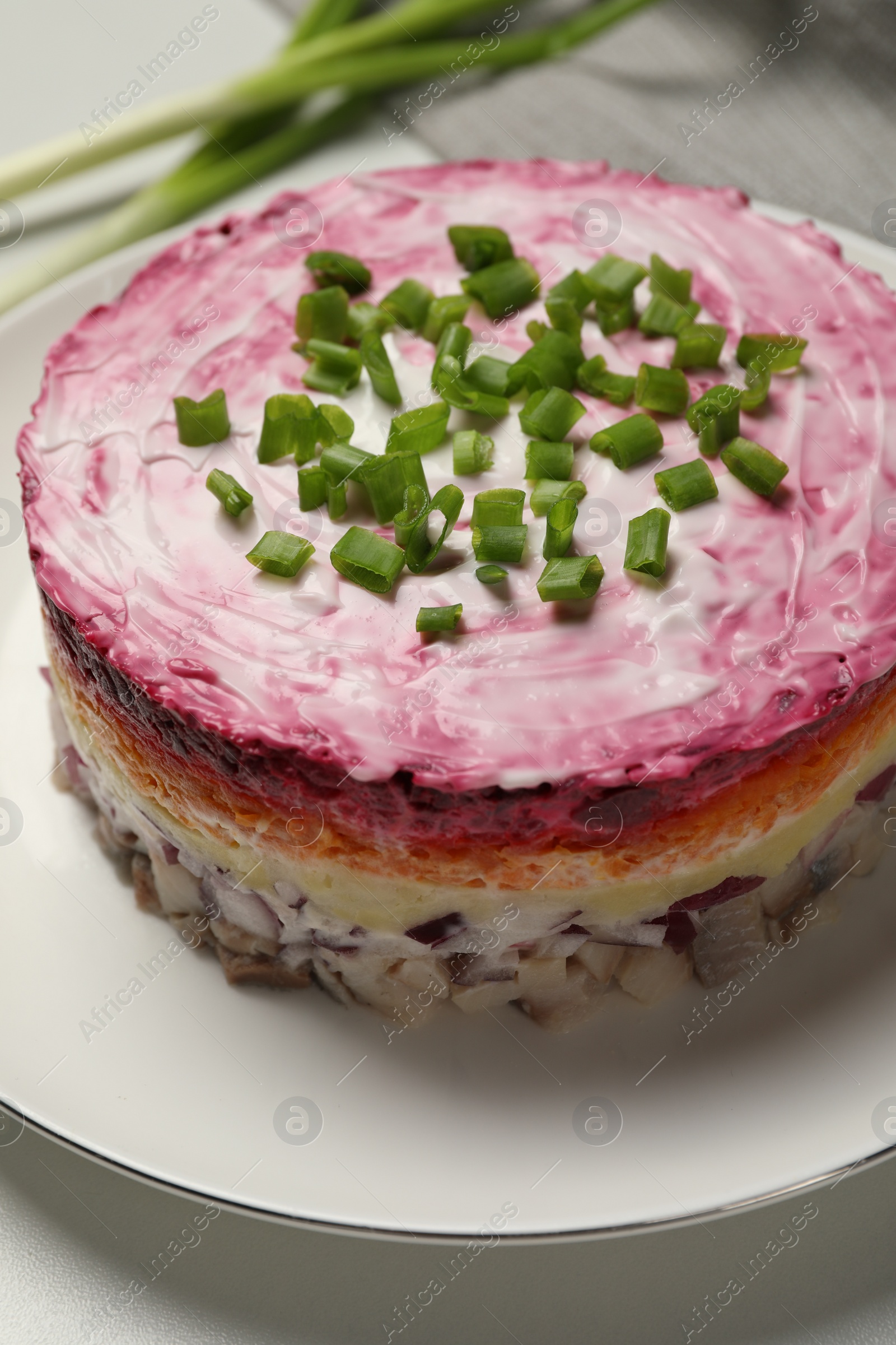 Photo of Herring under fur coat salad on white table, closeup. Traditional Russian dish