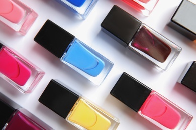 Bottles of bright nail polish on white background, top view