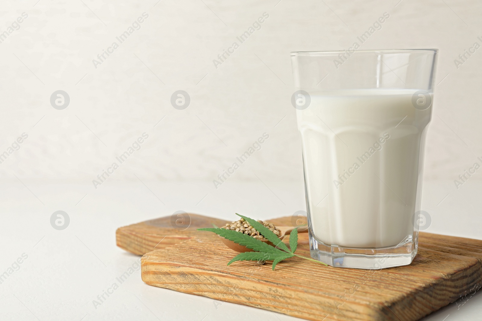 Photo of Composition with glass of hemp milk on white table. Space for text