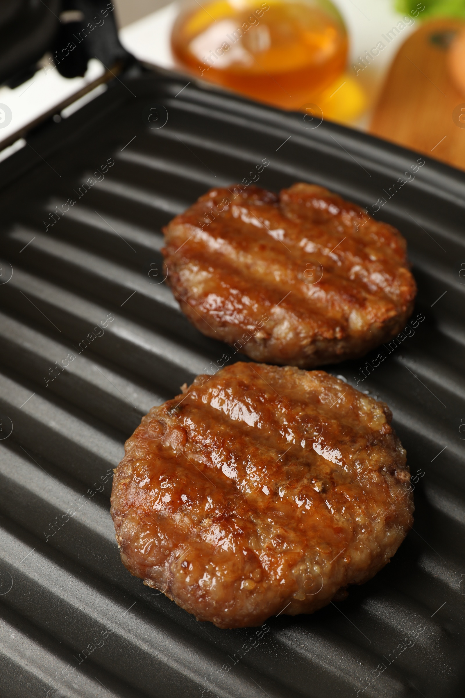 Photo of Delicious hamburger patties on electric grill, closeup