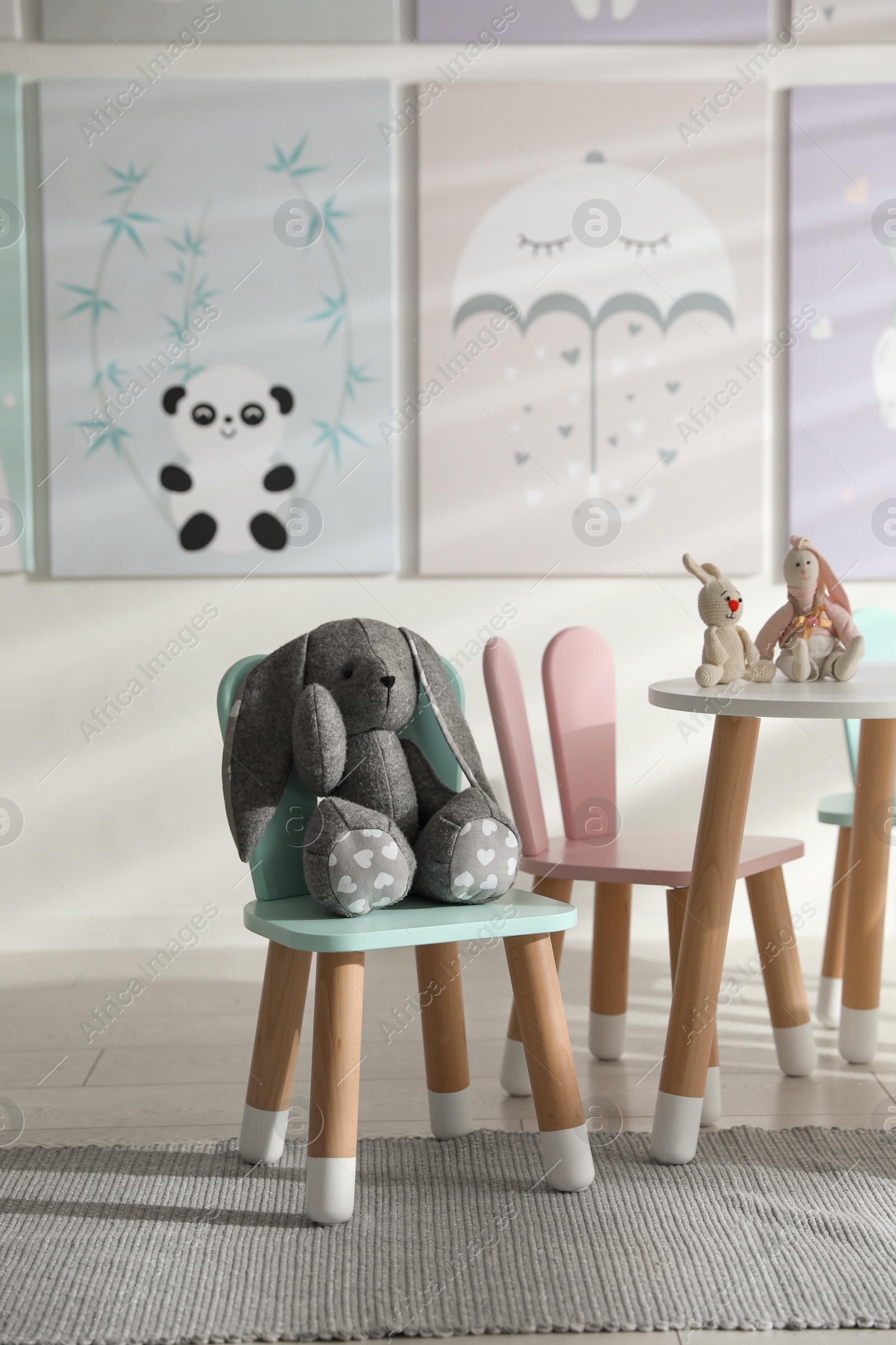 Photo of Small table and chairs with bunny ears in children's room interior