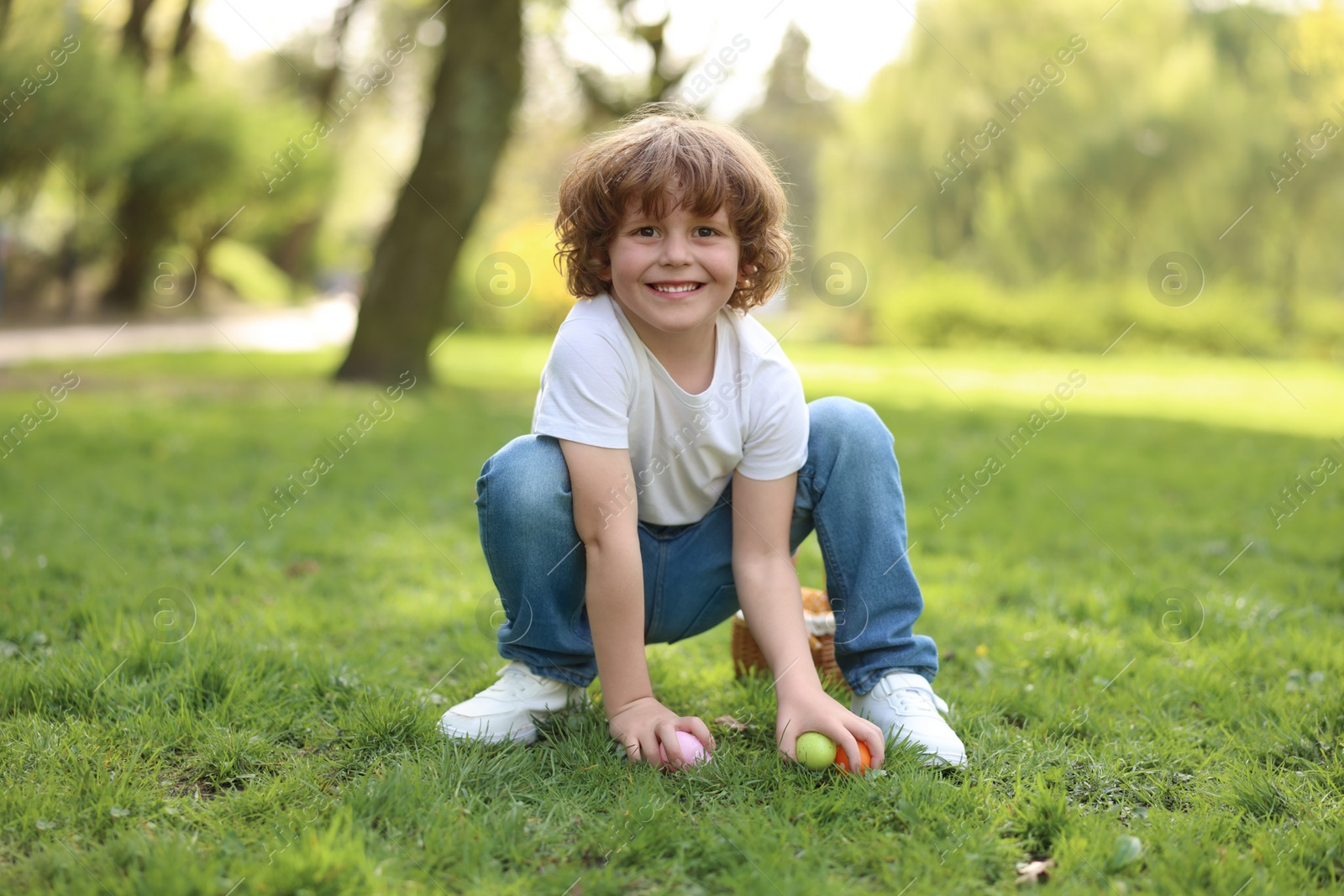 Photo of Easter celebration. Cute little boy hunting eggs outdoors