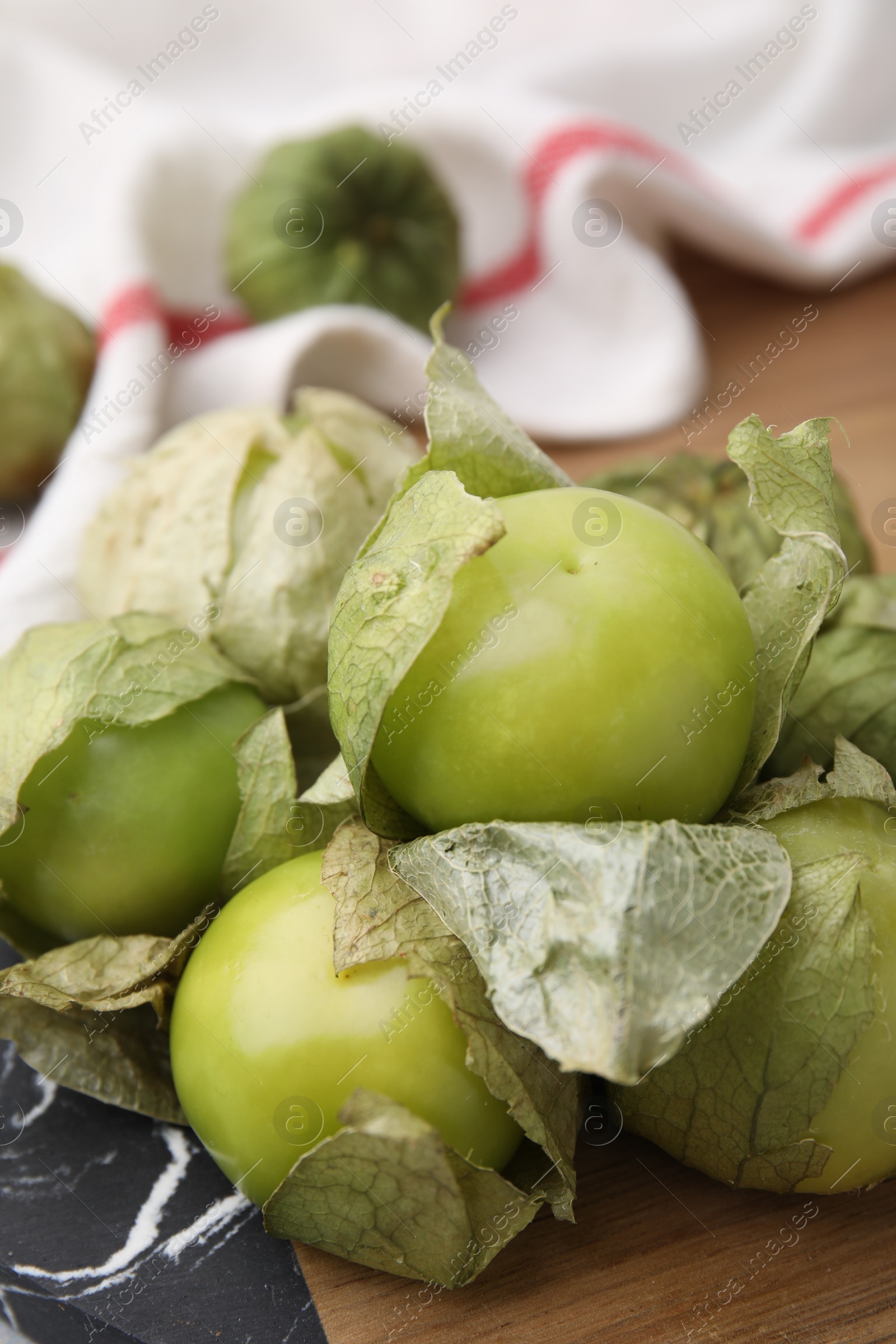 Photo of Fresh green tomatillos with husk on table, closeup