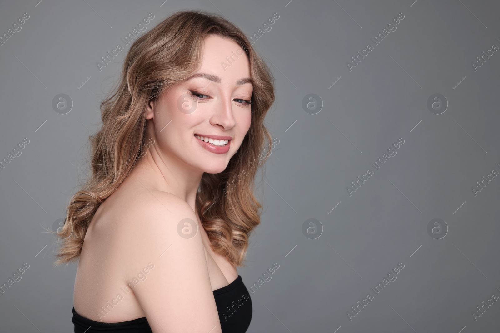 Photo of Portrait of smiling woman with curly hair on grey background. Space for text