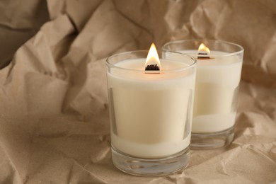Photo of Burning soy candles with wooden wicks on crumpled kraft paper