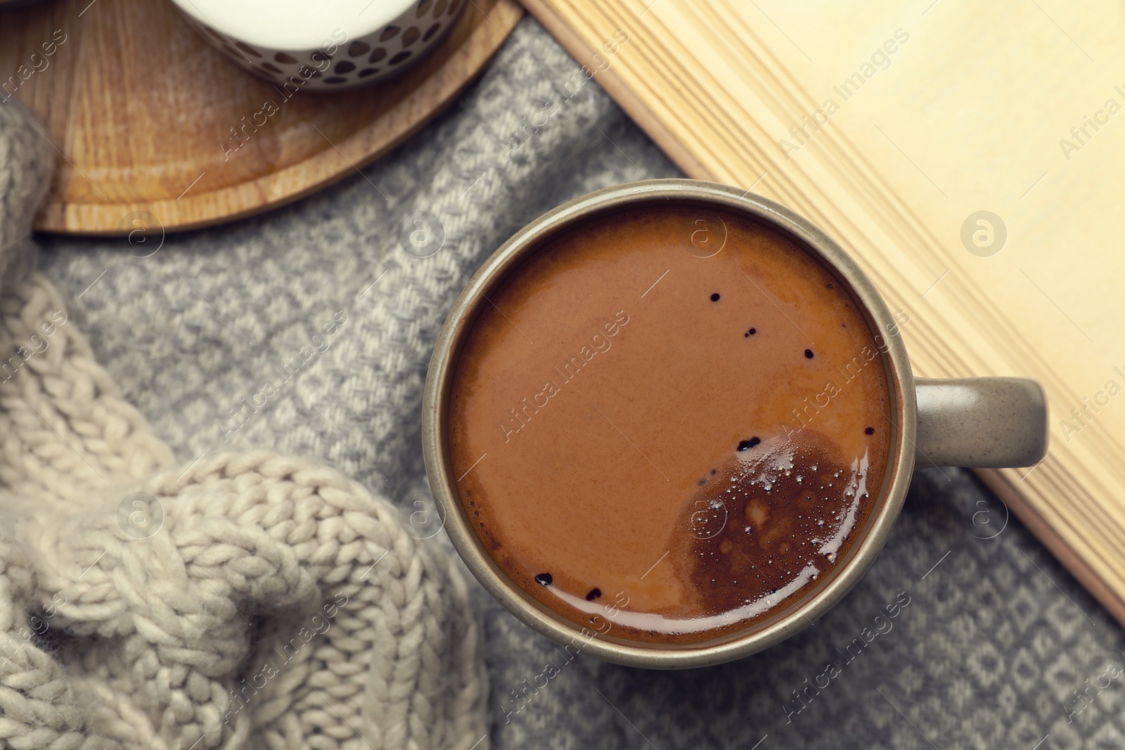 Photo of Cup of delicious hot winter drink on grey fabric, flat lay. Winter drink