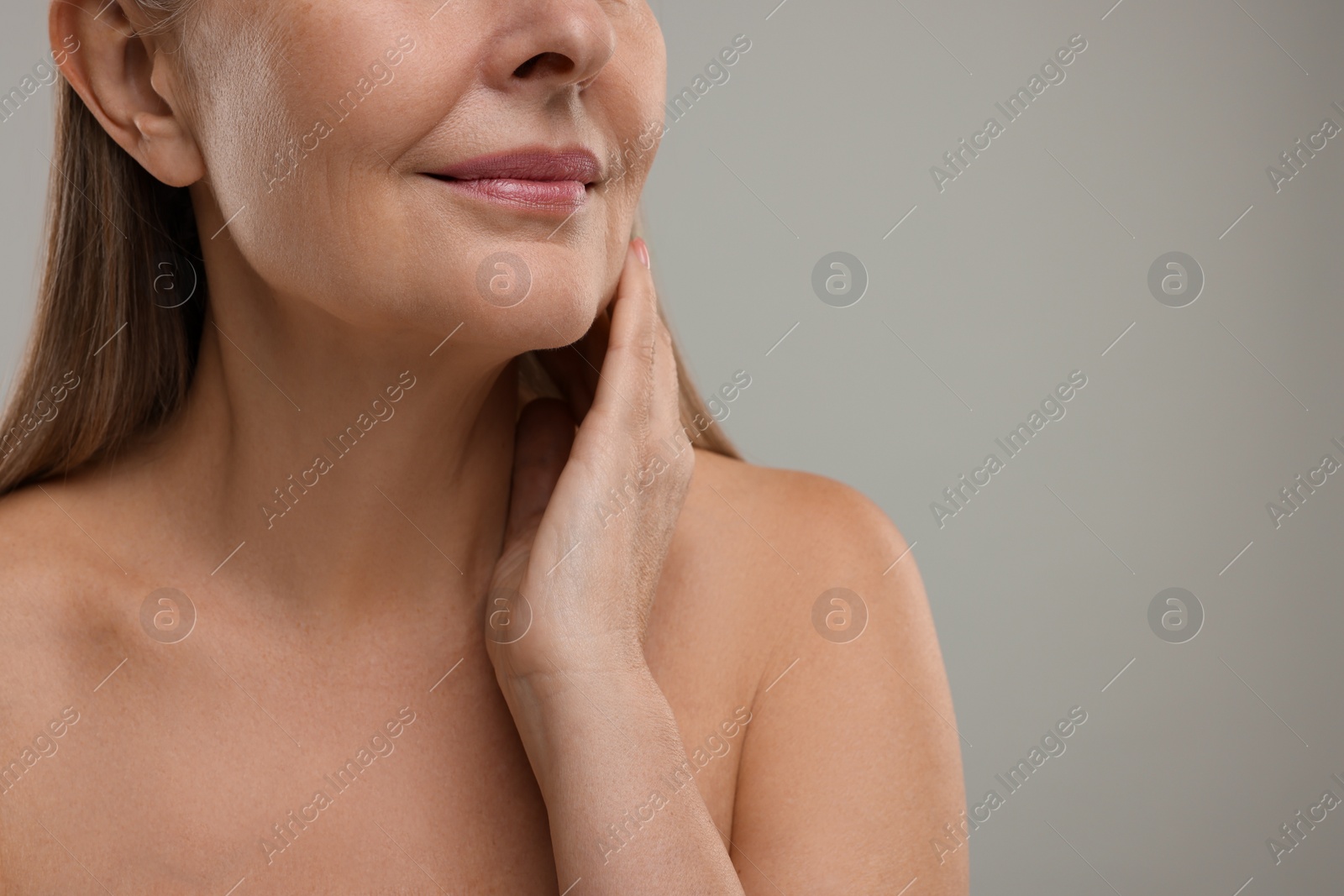 Photo of Mature woman touching her neck on grey background, closeup. Space for text