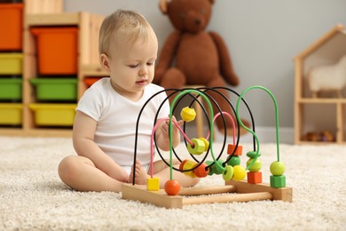 Children toys. Cute little boy playing with bead maze on rug at home