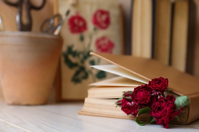 Photo of Beautiful dried flowers in book on wooden table