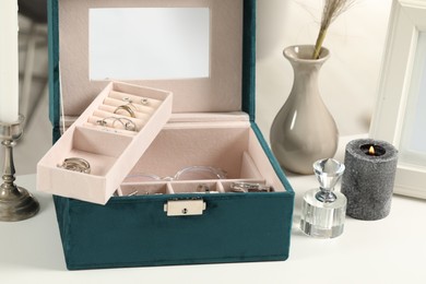 Photo of Jewelry box with many different accessories, perfume and decor on white table