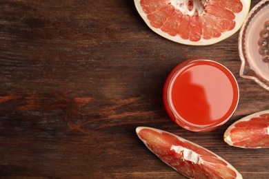 Glass of pink pomelo juice and fruit on wooden table, flat lay. Space for text