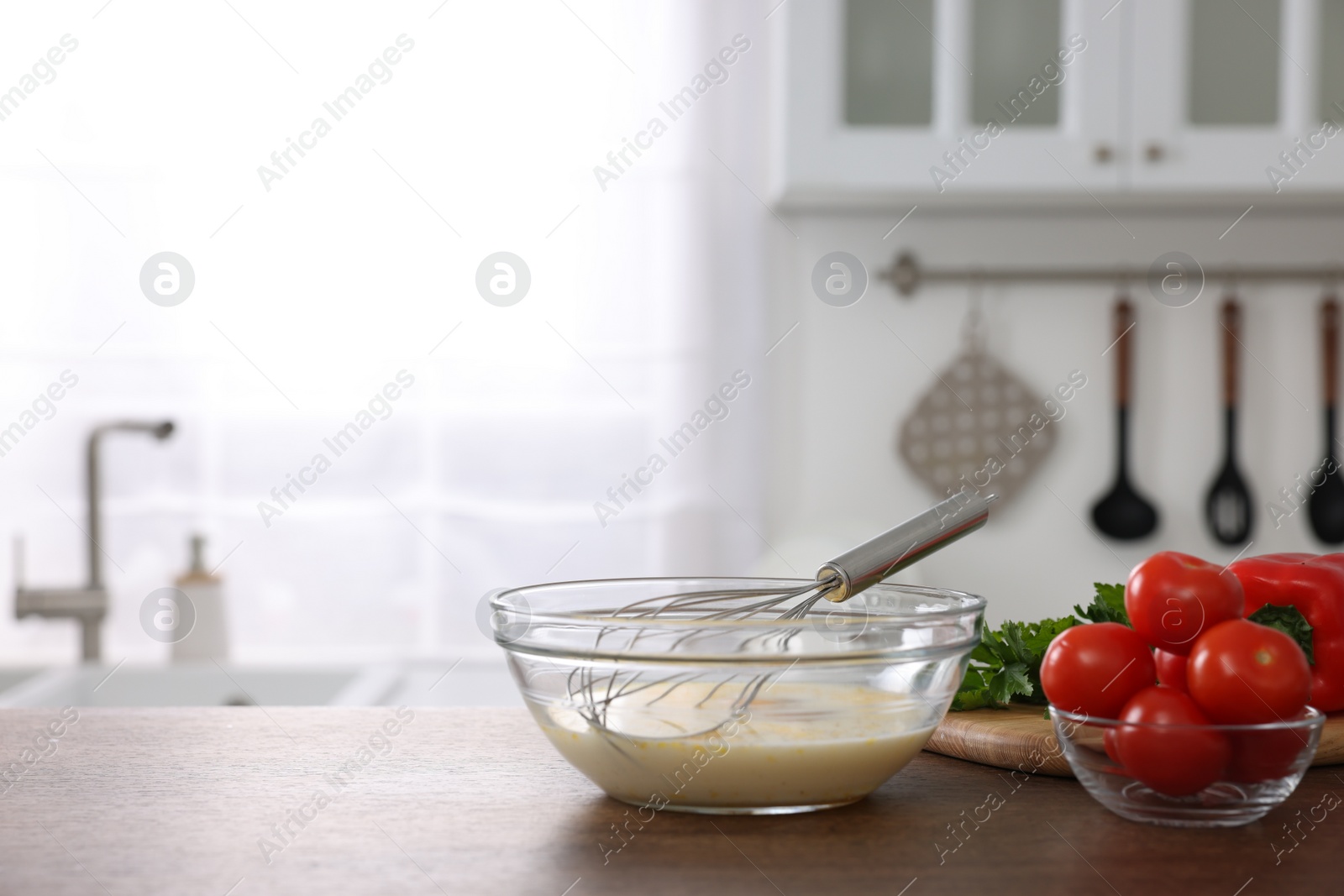 Photo of Whisk, bowl, beaten eggs and other ingredients on wooden table indoors, space for text