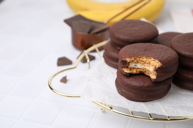 Photo of Tasty banana choco pies on white tiled table, closeup. Space for text