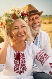 Photo of Happy mature couple wearing Ukrainian national clothes in field