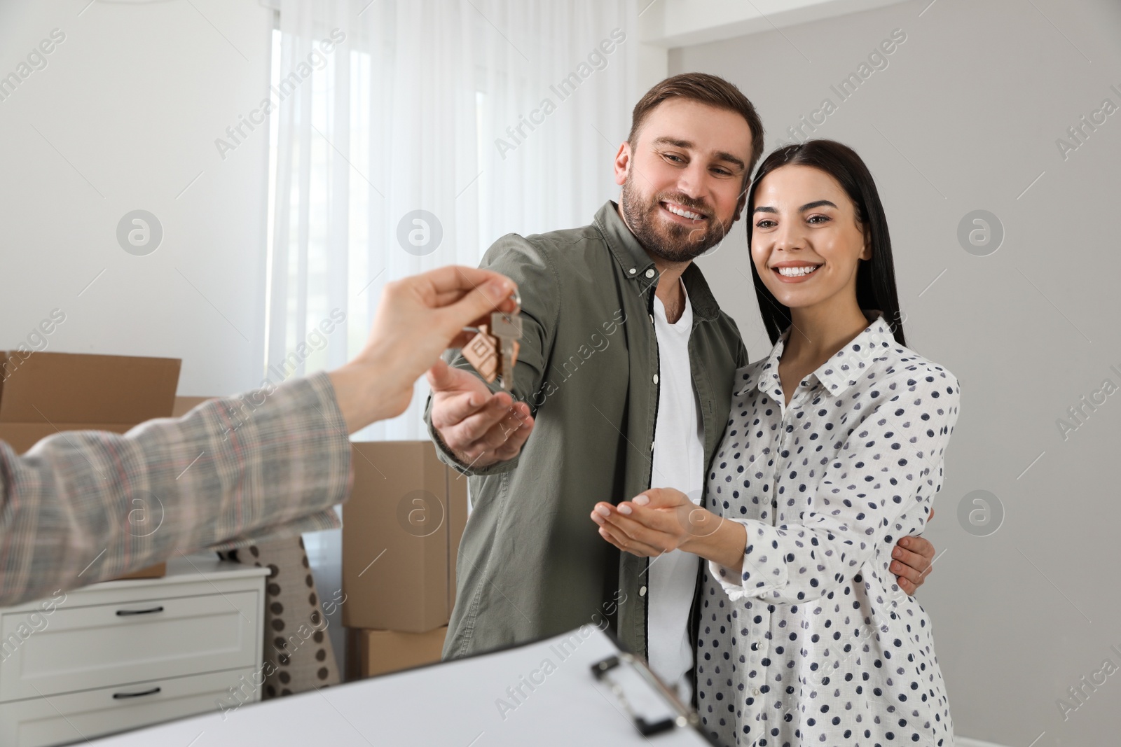 Photo of Real estate agent giving key to happy young couple in new house