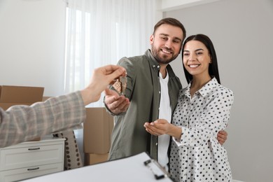 Photo of Real estate agent giving key to happy young couple in new house