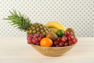 Photo of Fresh ripe fruits in bowl on white wooden table