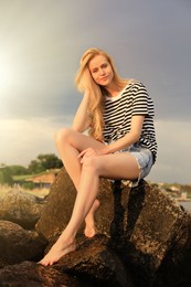 Beautiful young woman sitting on rocks outdoors