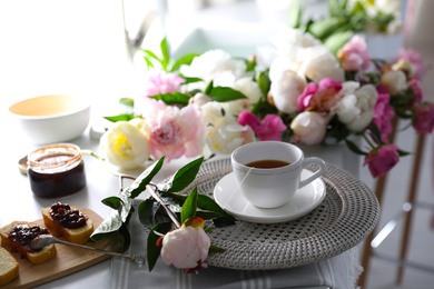 Photo of Beautiful peonies and breakfast on table indoors
