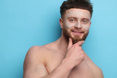 Handsome man with facial mask on his face against light blue background