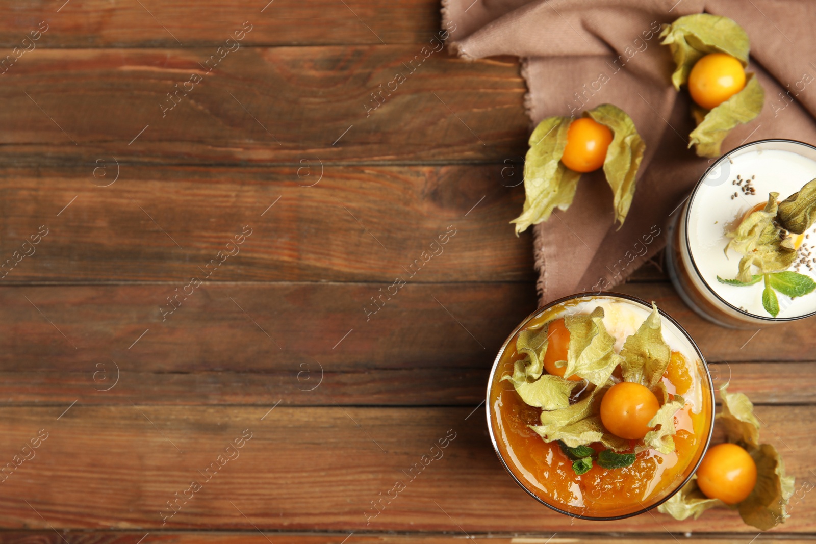 Photo of Delicious dessert decorated with physalis fruit on wooden table, flat lay. Space for text