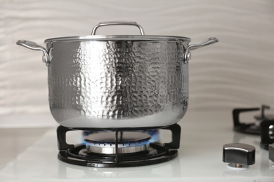 Photo of Shiny steel saucepan on modern gas stove