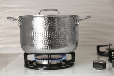 Shiny steel saucepan on modern gas stove