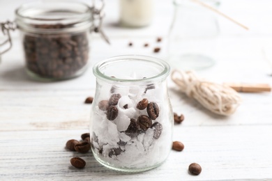 Glass jar, wax and coffee beans for making handmade candle on wooden table