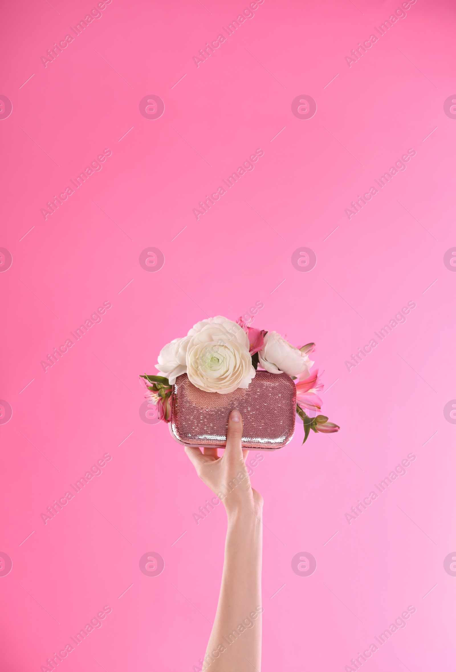 Photo of Woman holding elegant handbag with spring flowers on pink background, closeup. Space for text