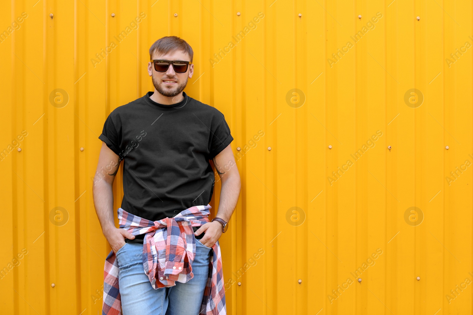 Photo of Young man wearing black t-shirt near color wall on street