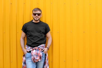 Photo of Young man wearing black t-shirt near color wall on street