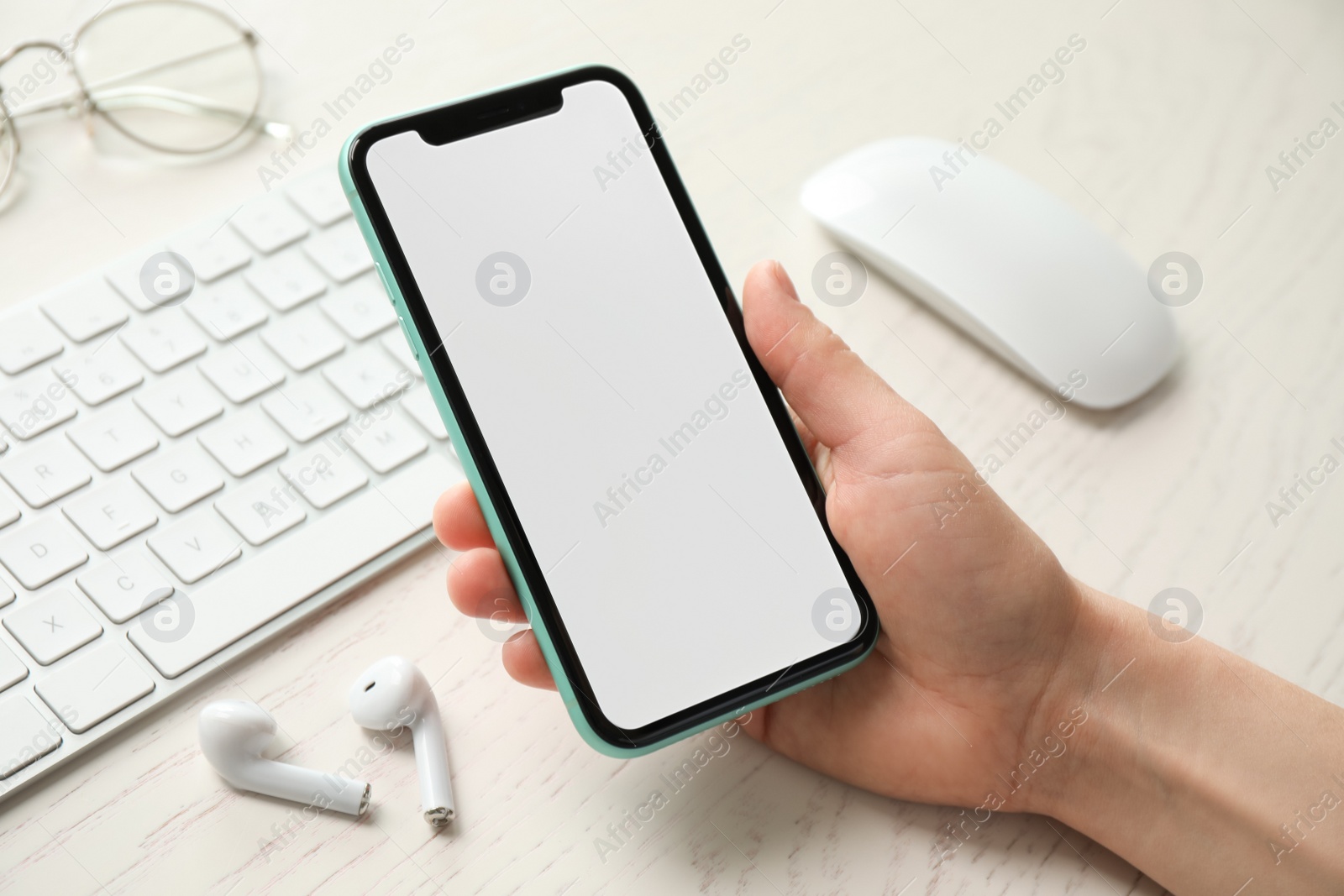 Photo of MYKOLAIV, UKRAINE - JULY 8, 2020: Woman holding Iphone 11 Pro Max with blank screen at workplace, closeup