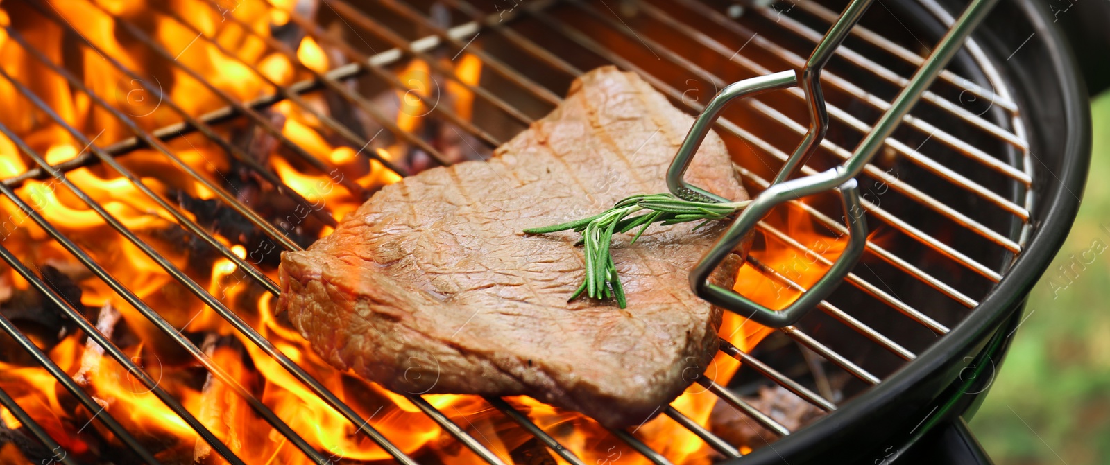 Image of Tasty meat on barbecue grill with fire flames outdoors, closeup. Banner design