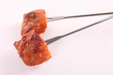 Photo of Fondue forks with pieces of fried meat on white background, closeup