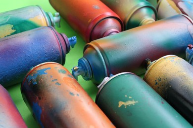 Photo of Many spray paint cans on green background