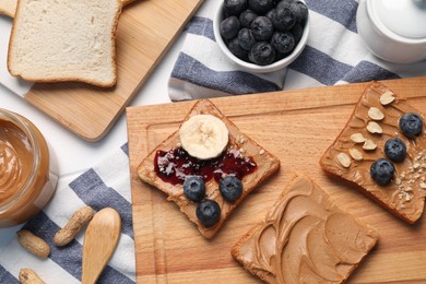 Photo of Different tasty toasts with nut butter and products on table, flat lay
