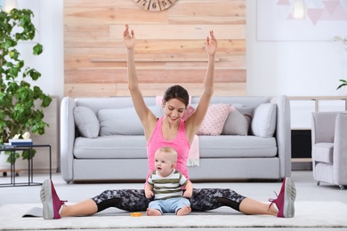 Photo of Young sportive woman doing exercise with her son at home. Fitness training