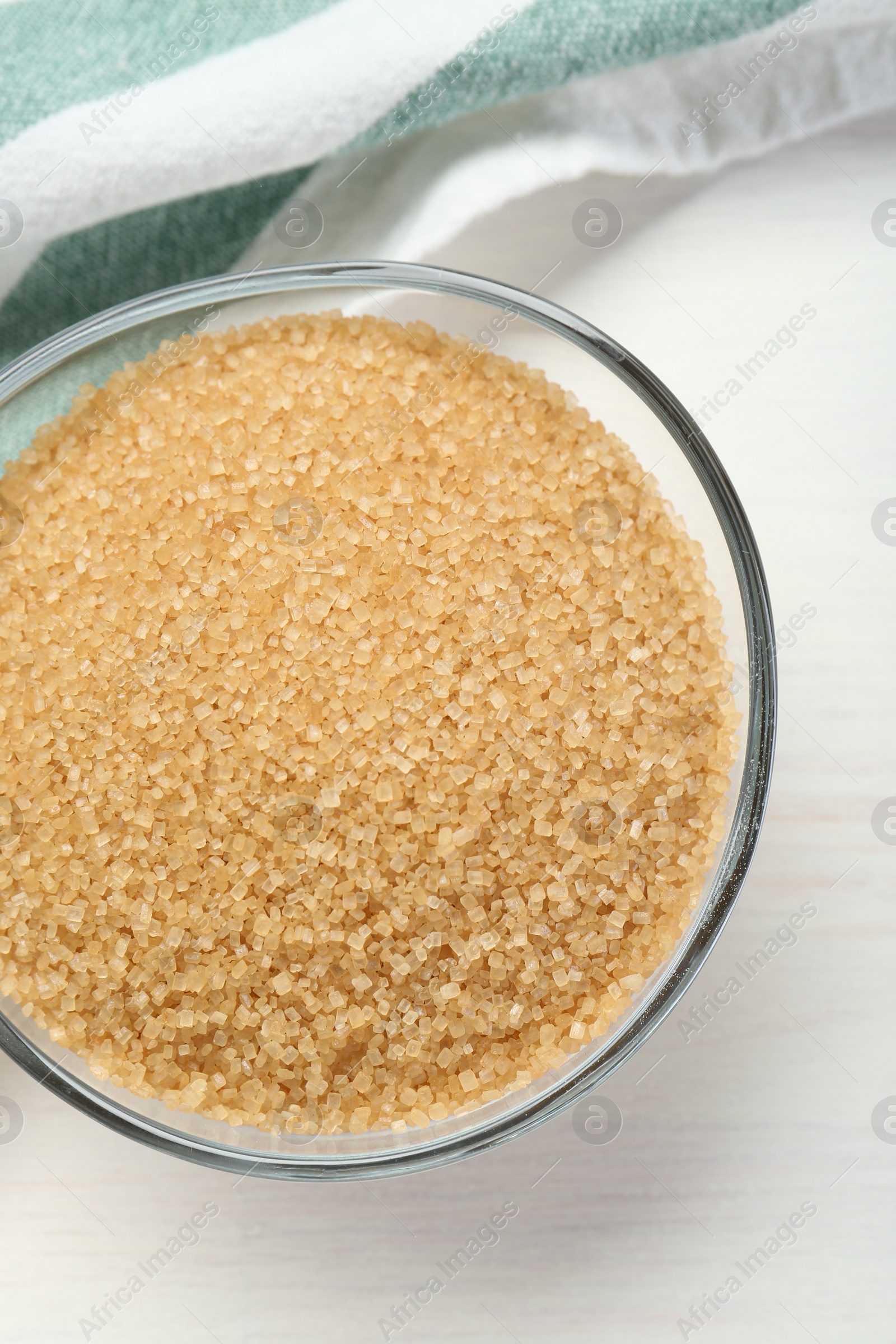 Photo of Brown sugar in glass bowl on white wooden table, top view