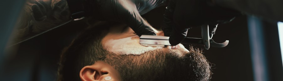 Professional hairdresser working with bearded client in barbershop, closeup. Banner design
