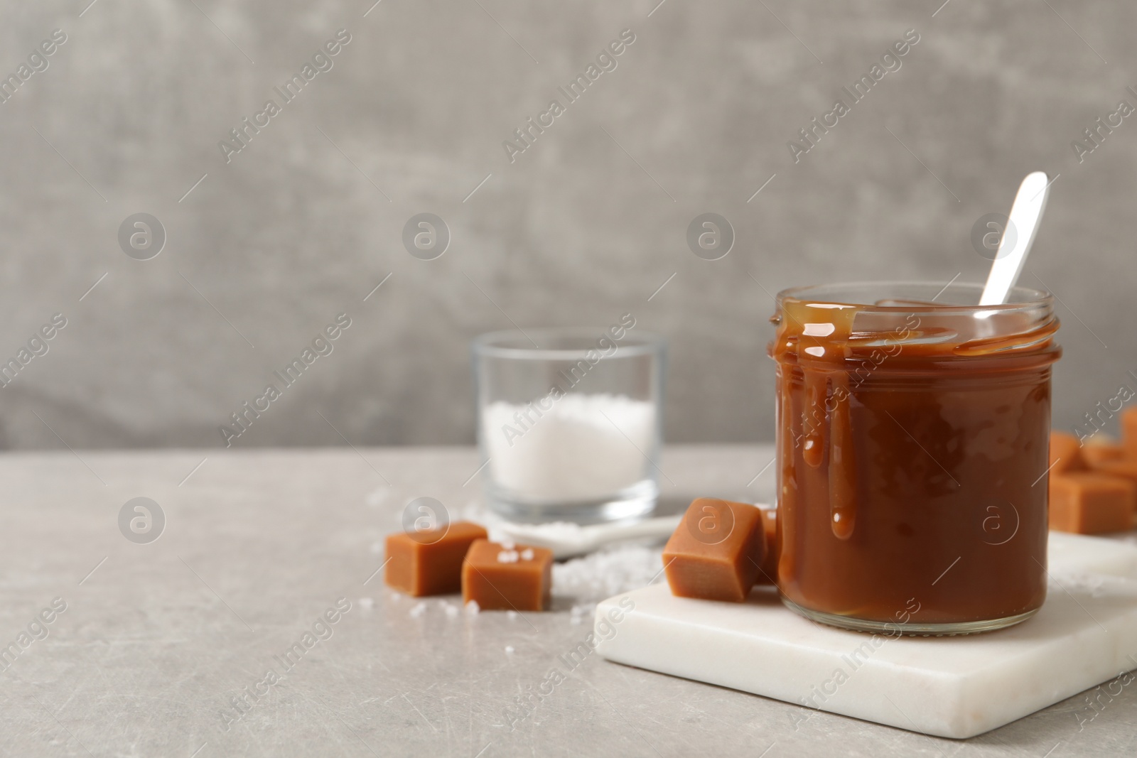 Photo of Tasty salted caramel on light grey table, space for text