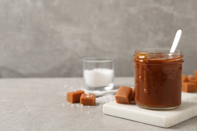 Tasty salted caramel on light grey table, space for text