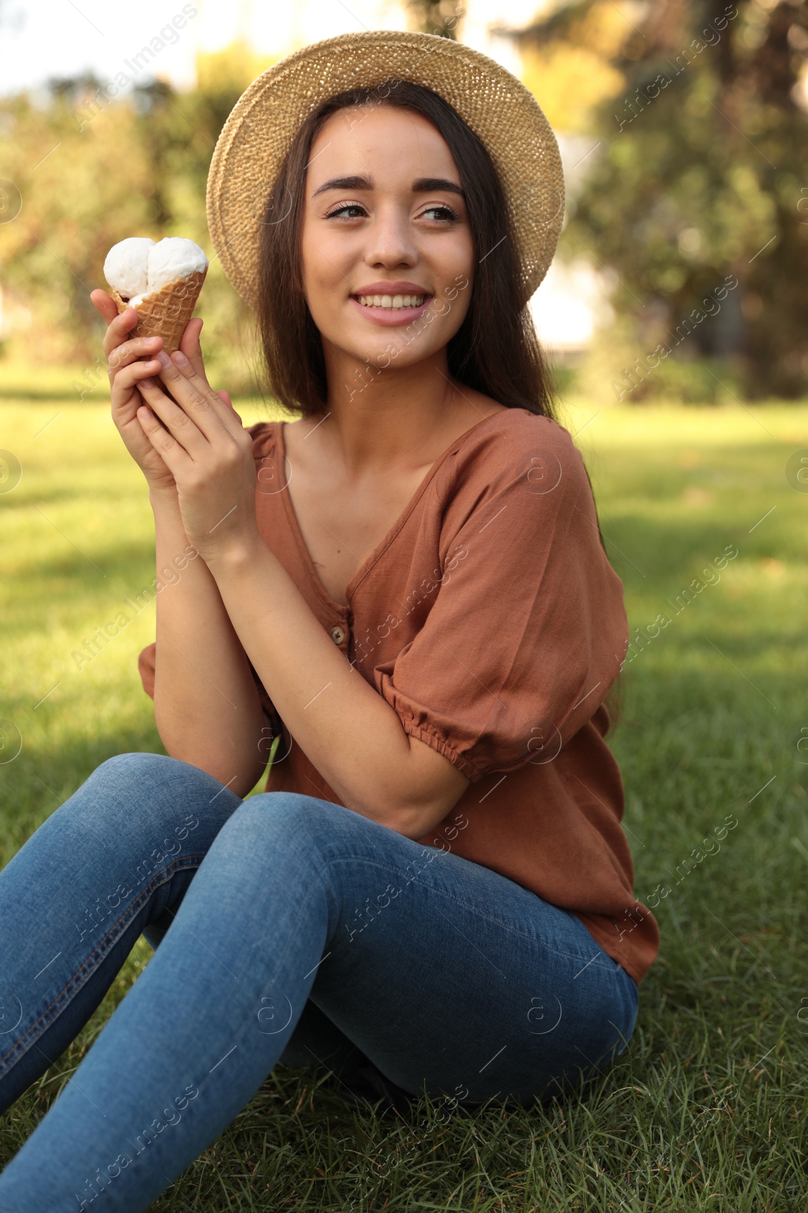 Photo of Happy young woman with delicious ice cream in waffle cone outdoors