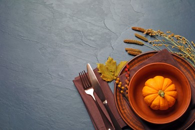 Photo of Autumn table setting with floral decor and pumpkin on dark grey background, flat lay. Space for text