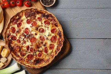 Photo of Delicious homemade prosciutto quiche and ingredients on gray wooden table, flat lay. Space for text