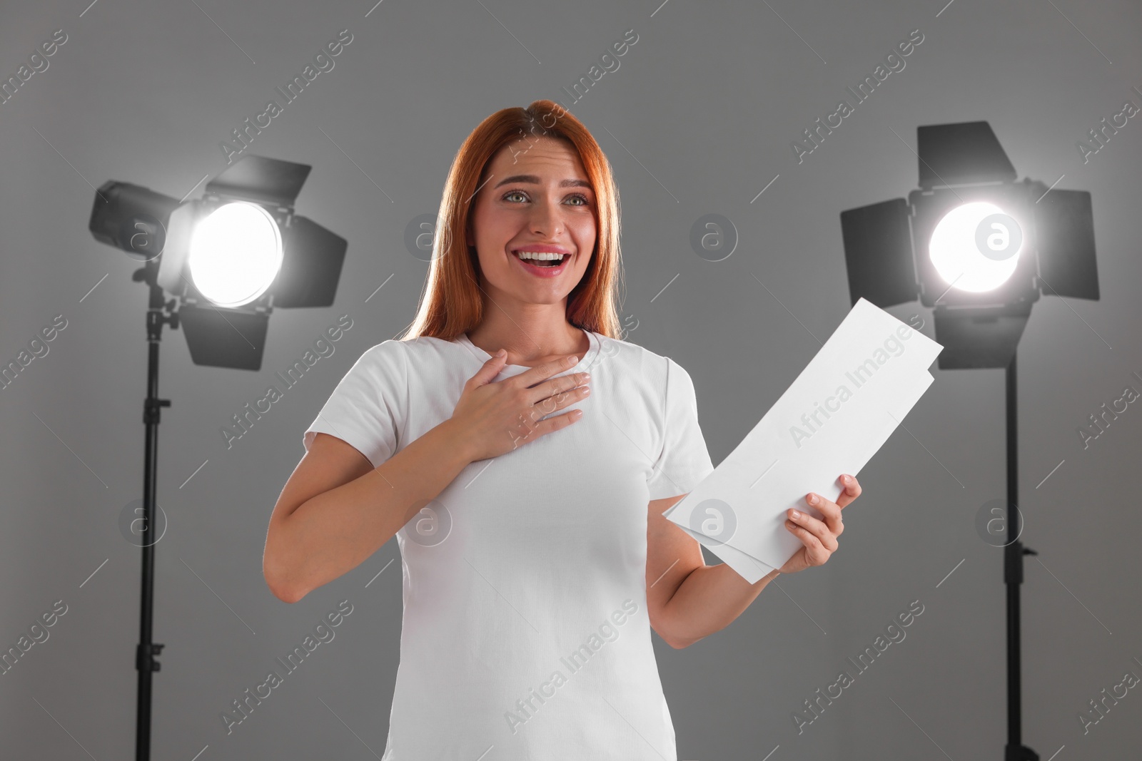 Photo of Casting call. Emotional woman with script performing on grey background in studio