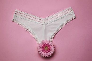 Photo of Woman's panties and gerbera flower on pink background, top view