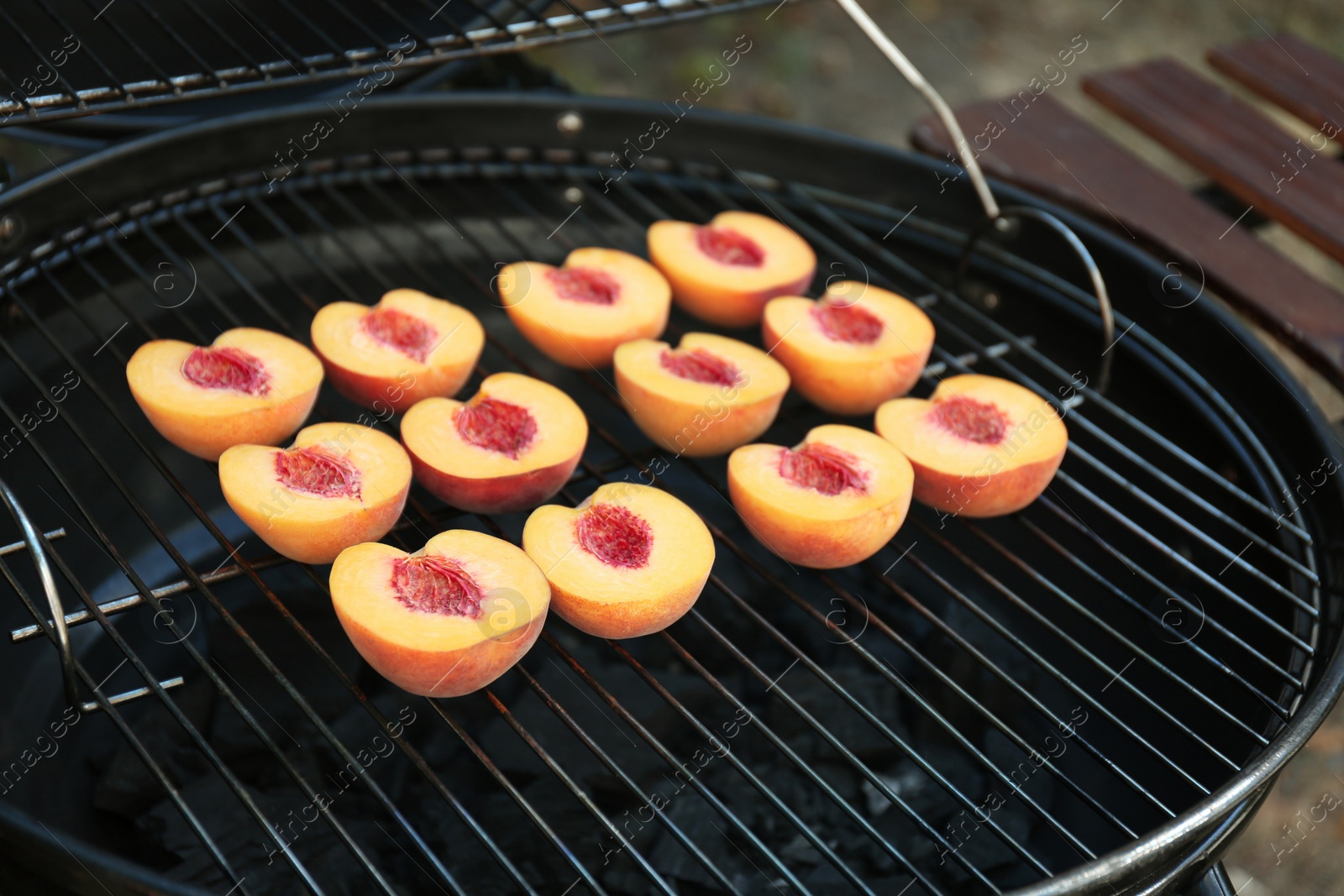 Photo of Modern grill with tasty cut peaches outdoors, closeup