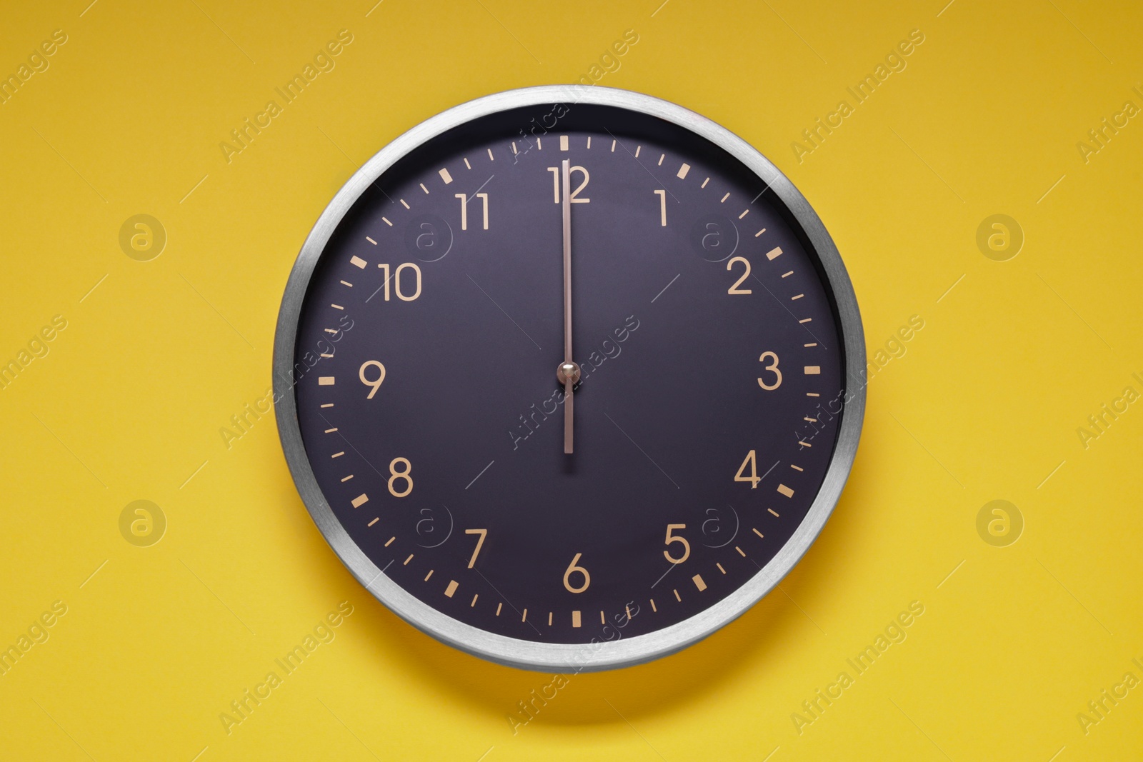 Photo of Stylish round clock on yellow background, top view. Interior element