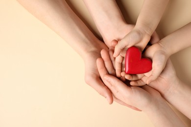 Photo of Parents and kid holding red heart in hands on beige background, top view. Space for text