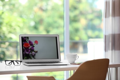 Photo of Comfortable workplace with modern laptop on desk in home office, space for text